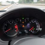 Gros plan sur le tableau de bord d’une voiture avec un voyant d’alerte lumineux, ambiance réaliste de conduite quotidienne et route légèrement floue à l’arrière-plan.